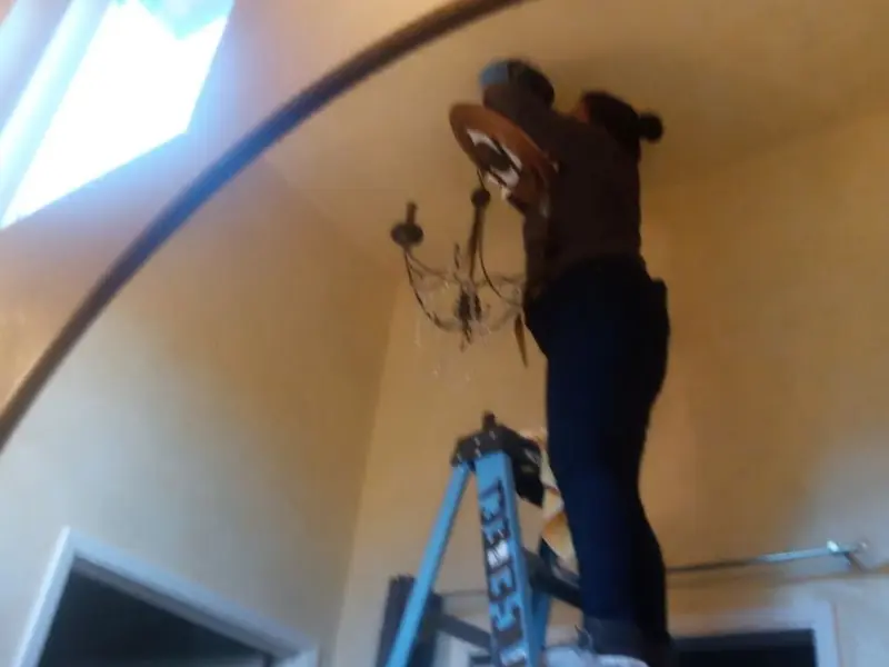Electrician installing a chandelier in a Erwin residence